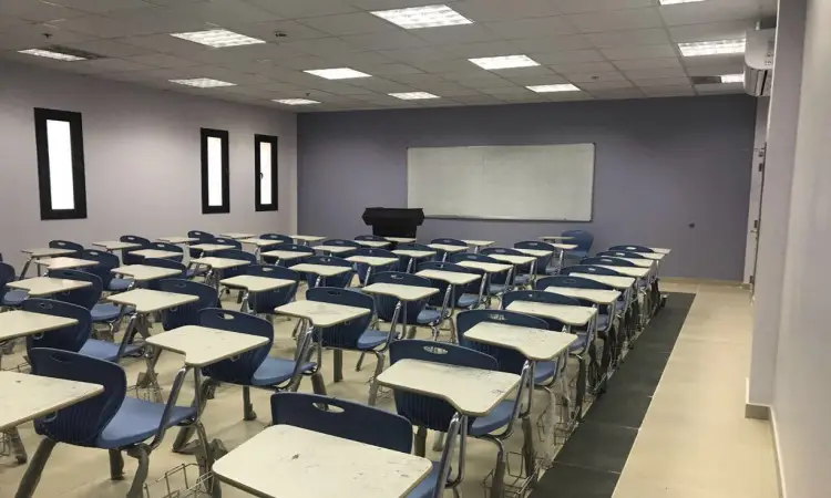 تُظهِر قاعة الصورة خالية في المبنى الجديد لكلية عقلية الصقور في القصيم، حيث تتراس صفوف الكراسي الزرقاء والطاولات بشكل منظم نيويورك السبورة ومنصة تحت إضاءة قوية من المصابيح الفلورية. ظهرت جدران البناء باللون الرمادي الفاتح، مع وجود ثلاث نوافذ على الجانب الأيسر لتعكس ملامح التصميم الأكاديمي الحديث للمبنى. يُلحظ أن مقاعد القاعة مهيأة لاستقبال الطلاب الذين يتأخرون عن الغترة أو الشماغ والعقال والبشت السعودي بما في ذلك تمكنهم من الوطنية الرسمية لطلاب الجامعة وأعضاء الهيئة التدريسية.