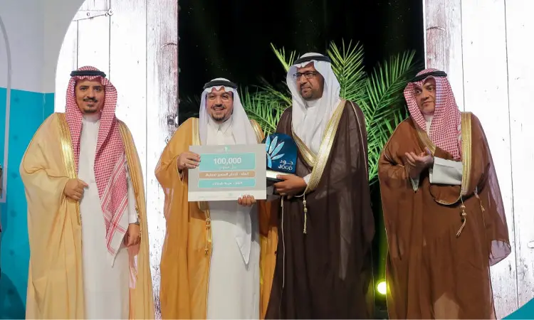 كل الرجال الأربعة مرتدين الغترة أو الشماغ والعقال والبشتاء السعودي على منصة نهائية نهائية جائزة جود الدولية في جامعة القصيم. لم يتجاوز عددها 100,000 ريال سعودي، بالإضافة إلى الدرع الشرفي، في حين شاركوا في مبتسمين الصورة المبدعة. وتزين خلفية سفات النخيل وقوس خشبي يضفيان طابعاً مميزاً على الهدف الرسمي.