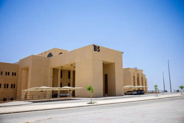 مبنى كبير ذو لون بيج بالضغط الرمزي B5، ومن المحتمل أنه يتبع لكلية التمريض في القصيم، وتوجد أمامه مواقف سيارات مظللة عدد من السيارات الصغيرة، ويحتمل هذا المبنى تحت سماء صافية زرقاء.