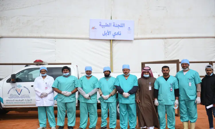 تتشرف مجموعة من المراجعين والمختصين من اللجنة الطبية في جامعة القصيم بالوقوف أمام عيادة الصيدلة المتنقلة ولافتة مهرجان الملك عبدالعزيز للإبل، وهم غياب زيهم الرسمي الذي يتضمن أطقم طبية فيروزي وغطاء رأس من القبعات الزرقاء والعاطفية البيضاء. كما يظهر مجموعة مرتدين الغترة أو الشماغ السعودي مع العقال، بالإضافة إلى البشت السعودي التقليدي، في تجسيد للهوية الوطنية الالتزام المهني من خلال مشاركتهم بالمهرجان.