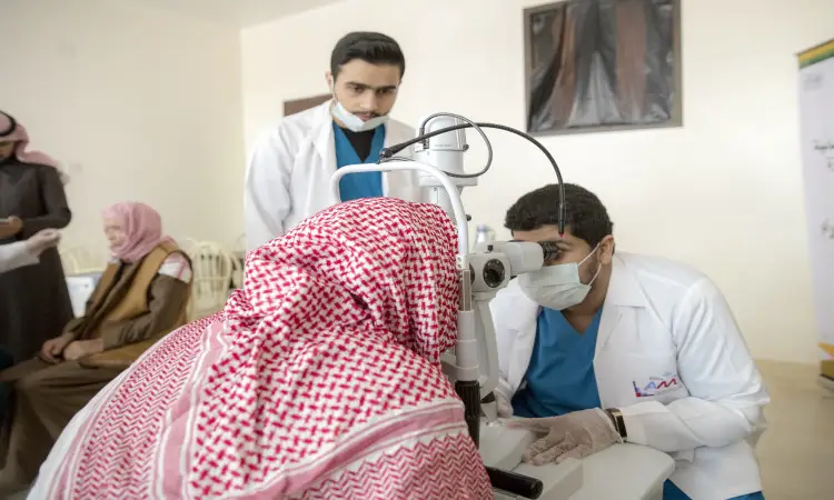 يقوم أحد من سوببي الرعاية الصحية مرتدياًاً أبيض وكمامة فحص أجهزة الطب المختص بإيتام المشاركين في المساعدة الطبية المتخصصة في دار رعاية كبار بمحافظة عنيزة، وذلك برفقة زميله الذي ارتدى الغترة السعودية والعقال والبشت السعودي، بعد متابعة عدد من المرضى دورهم في الخلفية.