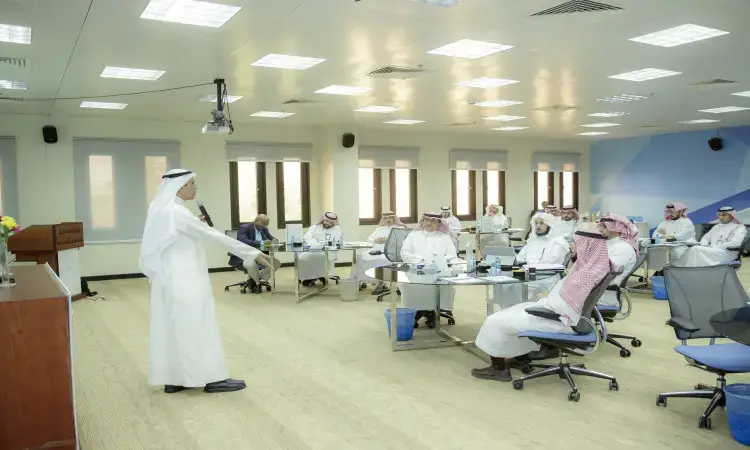 رجل القط مرتداً الغترة السعودية والعقال والبشت السعودي في قاعة المؤتمرات الحديثة في القصيم، متشوقاً كلمته لجمهور الرجال الذين يلبسون الشماغ السعودي والعقال، ويتناول في حديثه دور شركاء التنمية المحلية وأهمهم في تحقيق التنمية الاجتماعية.