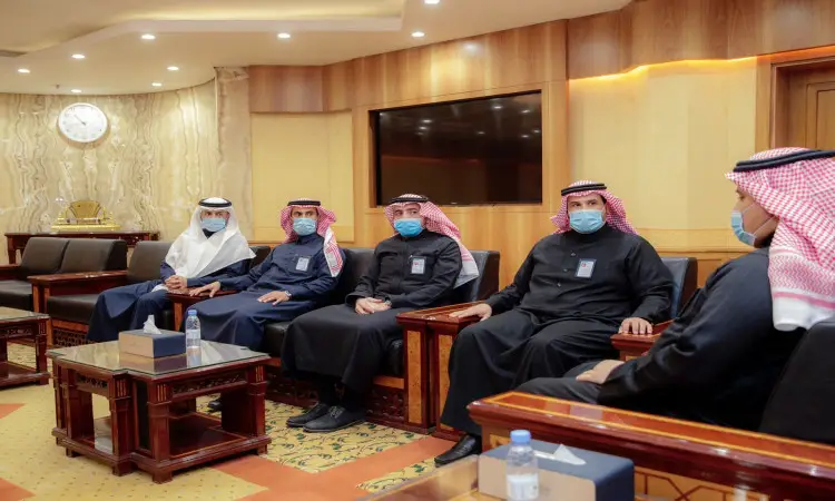 يجتمع خمسة رجال غترة أو شماغاً سعودياً مع عقال، بالإضافة إلى البشت السعودي، وهم يضعون الكمامات الواقية، على أرائك داخل قاعة السيدات. ولم يناقش الفريق إنجازاتهم المتميزة ومن ثم تحقيق الميدالية الذهبية في معرض إيتكس 2021، وذلك من خلال حضور ساعة حائط كبيرة وشاشة تلفزيون في خلفية القاعة.