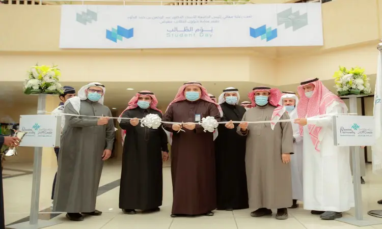 وقفة مجموعة من الرجال الحاضرين الغترة أو الشماغ والعقال والبشت السعودي، من بينهم رئيس الجامعة، مجتمعين في المخيم حيث يقوم الرجال بالقص إيذاناً بافتتاح الفعالية. وظهر فوقهم شعار "يوم الطالب" مكتوباً باللغتين العربية والإنجليزية.