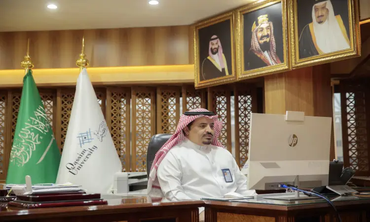 رجل يرتدي غترة سعودية وعقال وبشت سعودي رسميًا إلى مكتبه في أحد مكاتب جامعة القصيم، وأمامه جهاز حاسب آلي، كما يعيش خلفه أعلام المملكة العربية السعودية والجامعة، بالإضافة إلى صور قيادات الوطن. ويعكس الاهتمام المثير للاهتمام مهارات اللغة العربية ويشارك فيها الجميع دوليًا.