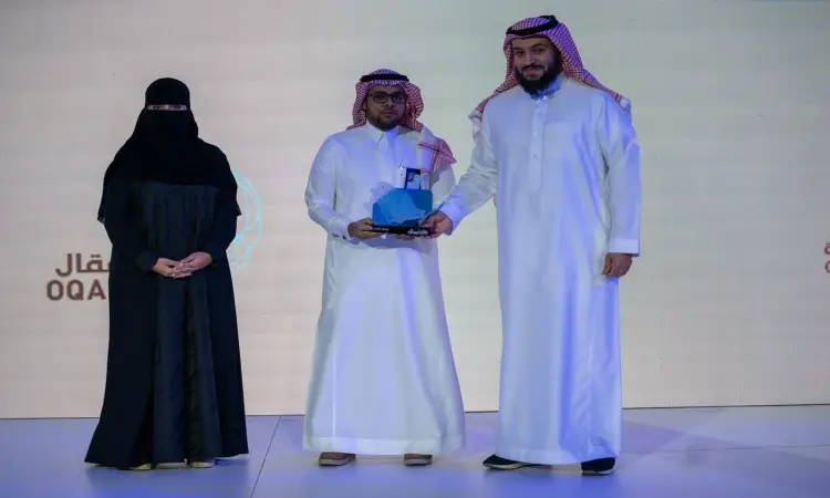 يجتمع ثلاثة أشخاص بزي سعودي على المنصة؛ ارتدى الرجل في تصفيات شماغاً وبشتاً سعودياً ويحمل جائزة زرقاء عن مشروع "ناصية". يقوم الرجل على يمينه، ويرتدي أيضاً الغترة والعقال والبشت السعودي، ويحقق النصر. أما السيدة الواقفة إلى فارس فتوشحتة بيضاء ونقاباً تحتفي بروح الإدعاءات لإختراعها في هذا المقام المقام في القصيم.