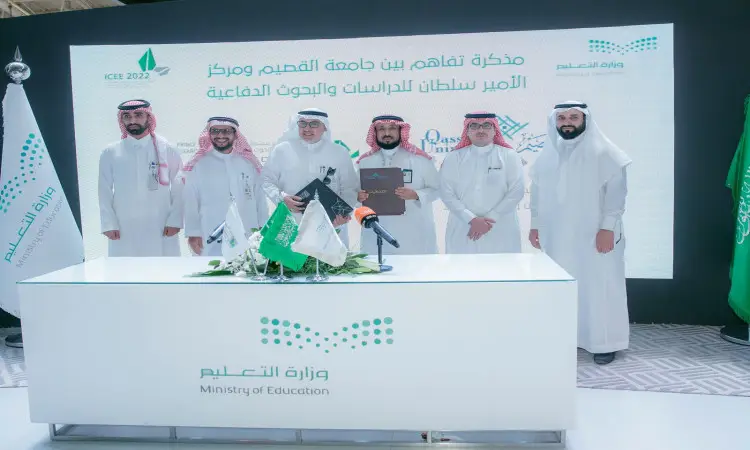 القطة جمع من الرجال مرتدين الغترة أو الشماغ السعودي مع العقال والبشت السعودي خلف مكتبٍ تعلوه وثائق وأعلام، وذلك للمرة الأولى خلال الفعاليات المؤتمر الدولي للتعليم توقيع وتعاون بين جامعة القصيم ومركز الأبحاث.