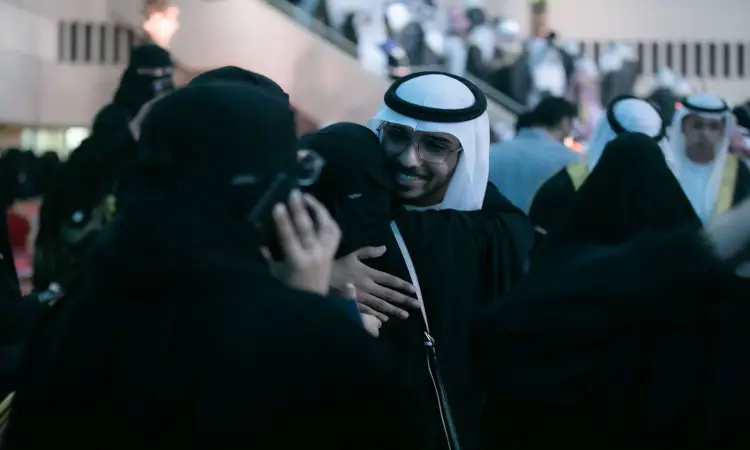 رجل للاتصال بزيٍ سعودي تقليديّ يرتدي غترةً سعودية، عقالاً وبشتاً أنيقاً ويبتسم وهو يعانق إحدى اللجان، التي قد تكون من أمهات الخريجين، وذلك وسط جمع من الحضور في ثقة تخريج الدفعة داخل قاعة الجامعة. وأشار بعض المشاركين إلى أنهم يخصصون تخصيص أصواتهم ويتبادلون الأحاديث في ما يسودها الفخر والسرور بمناسبة هذا الإنجاز الأكاديمي في جامعة القصيم.