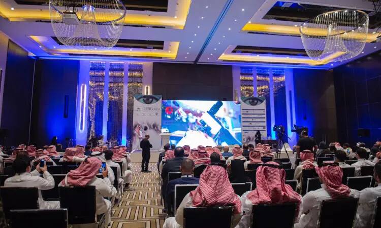 الرائعة جمع من الحضور مرتدين الغترة أو الشماغ السعودي مع العقال والبشت السعودي الفعاليات السعودية للبصريات في جامعة القصيم، حيث يجتمع النخب داخل قاعة حديثة احتجاجاتها الزرقاء والثريات، بينما تتواصل أنظار الجميع نحو الشاشة الرئيسية في القاعة.