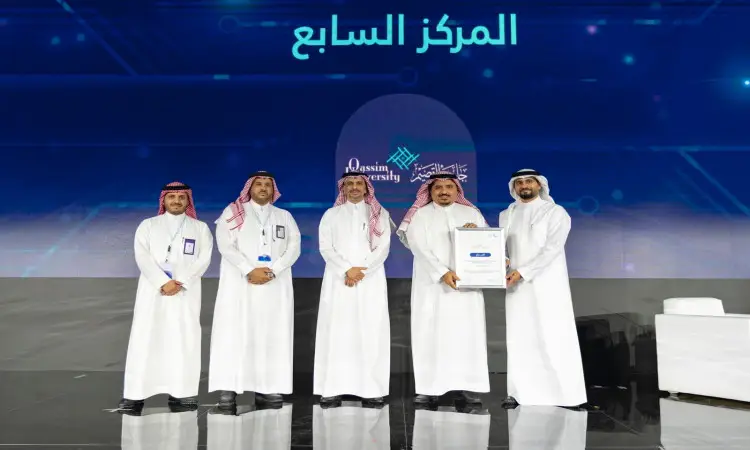 جميع الرجال خمسة رجال مرتدين الغترة أو الشماغ والعقال والبشت السعودي على المنصة، محددين ممسكًا بشهادة الشرف. وتبرز في الخلفية شاشة رقمية تحمل نصوصًا عربية وشعار جامعة القصيم، مع إشارات لقياس رقمي في التعليم المفيد.