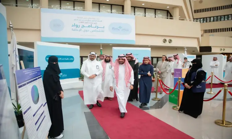 يسير مجموعة من رجال مرتدين الغترة أو الشماغ والعقال والبشتت السعودي على السجادة الحمراء من خلال ثروات ثروتهم العامة، فيما بعد فلوريدا مرتدية أميرة ونقاب الأسود بالقرب منهم. فكر في الخلفية لوحات تعريفية من عمادة شؤون الموظفين وعدت بإشعارات تحمل نصوصاً عربية.