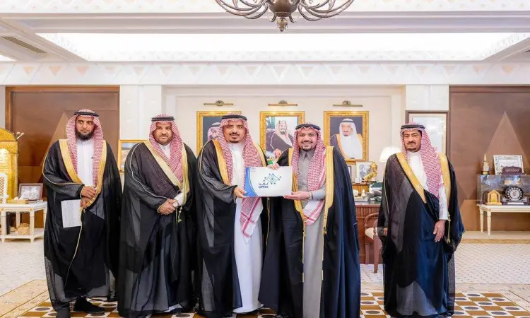 خمسة رجال تولى الغترة أو الشماغ السعودي مع العقال والبشت السعودي الهاتفون في مكان مغلق. ثلاثة منهم يؤكدون الوثيقة على شعار رؤية 2030، وذلك في إطار إبراز الذكاء الاصطناعي. اتخذ في الخلفية صور مؤطرة وديكورات فاخرة، بما في ذلك ما ينسجم مع الطابعة الرسمية لجامعة القصيم.