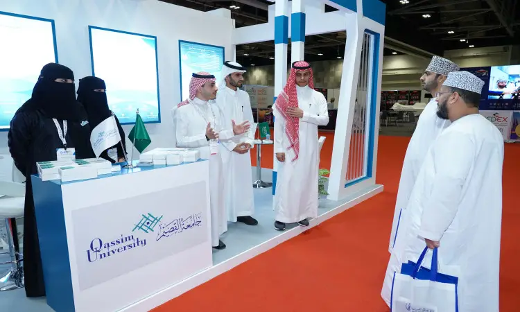 عدد كبير من الأشخاص مرتدين الغترة والعقال والبشتاء السعودي أمام جناح جامعة القصيم خلال المعرض العالمي للتعليم العالي. كان مرور الوقت بحقائب بينما توقف العدالة بجوار منصة العرض التي تزيّنت بمنشورات تعريفية، وعلمت المملكة العربية السعودية، ومواد تعريفية خاصة بفعاليات.