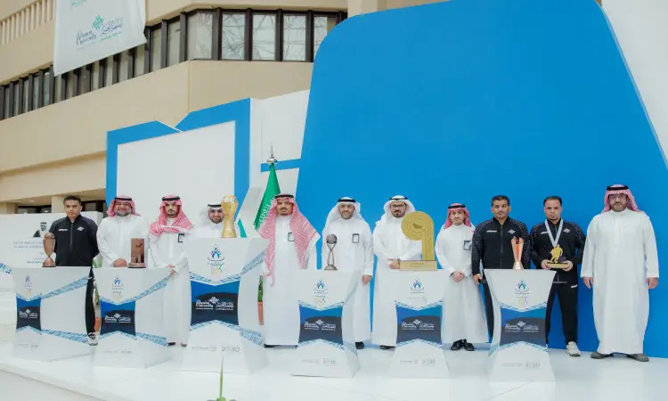 مجموعة من الرجال الغتيرة أو الشماغ السعودي مع العقال والبشتاء السعودي، إلى جانب الضيوف ببدلات، ومن بينهم صناع الإنجازات الرياضية؛ اتصلوا على المنصة خلال حفل رسمي في القصيم، وذلك لحضور شعارات ومضات الجامعة وأعمدة التتويج، ويعرضون الجوائز وكريمات تقديرًا لإنجازاتهم الرياضية.