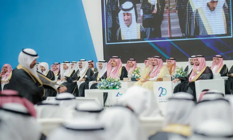 يجلس عدد من الرجال مرتدين الغترة أو الشماغ السعودي مع العقال والبشت السعودي، يتقدمهم سمو الأمير فيصل بن مشعل، على منصة في تخريج لجامعة القصيم، حيث تزين المنصة تنسيقات الزهراء الفاخرة لوضع خلفهم شاشة كبيرة. المساهمة في فريق الحضور من الحضور الرسمي السعودي.
