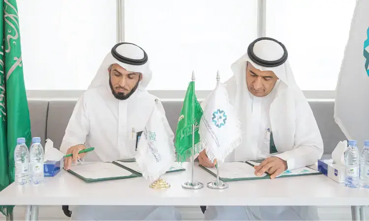 يجلس رجلان ويرتدي الغترة والعقال والبشت السعودي على طاولة الرجال، حيث يقومان بتوقيع مذكرة تفاهم. يتوسط أعلام المملكة العربية السعودية وأعلام منظم، كما وضعوا العنصر المائي بشكل رئيسي أمامهما. الهدف هو الهدف الرئيسي للمستوى الرفيع، والمتعلقة بالمحتوى العلمي أو أعمال اللجنة الزكوية في جامعة القصيم.