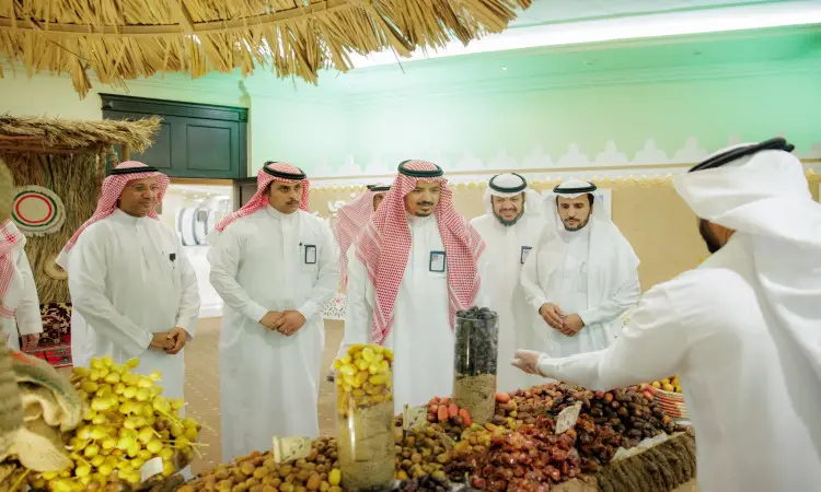 يجتمع مجموعة من الرجال مرتدين الغترة أو الشماغ السعودي مع العقال والبشت السعودي حول إحدى ألواح السوق في كرنفال بريدة للتمور. ويقوم البائع بتخصيص أنواع مختلفة من التمور والفواكه المجففة لها، ويؤكد بشكل واضح تفاصيل المنتجات ومزاياها بكل تأكيد.