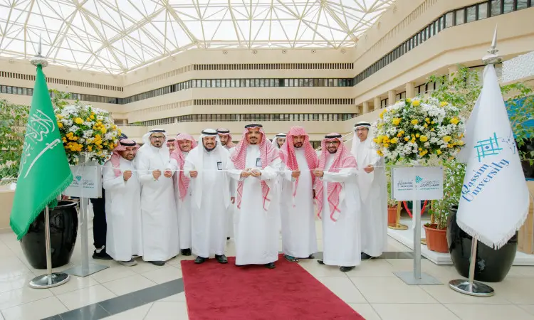 يجتمع عدد من الرجال مرتدين الغترة أو الشماغ والعقال والبشت السعودي في افتتاح رسمي داخل مبنى الجامعة، حيث يبتسمون ويلتقطون صورة جماعية خلال مراسم قص الشريط الأحمر إيذانًا بتدشين برنامج "طموح"، وتزين هدفهم على بساط أحمر بين منصتين للزهور، مع رفع علم المملكة العربية السعودية وعلم جامعة القصيم على المنصة الجانبية.