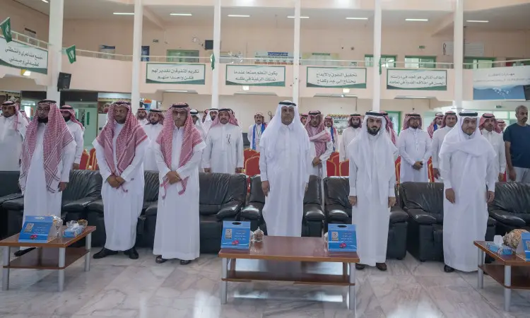 يصطف جمع من الرجال مرتدين الغترة أو الشماغ والعقال، كما اجتمعت البشت السعودي العالمي، في صفوف منظمة داخل قاعة تتزين بالأعلام والرايات السعودية، احتفاءً باليوم للمعلم. احترس من القاعة كراسٍ شاغرة، أثناء الجلوس أو الاتصال بعدد من الحضور والمعلمات وسائر الحضور في الداخل، وذلك داخل تليق بمكانة جامعة القصيم.