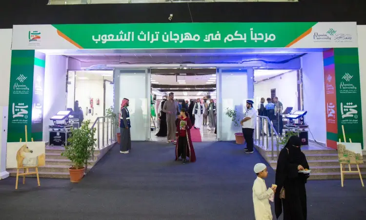 يدخل جمع غفير، ويضم طلاباً يمثلون تسعين دولة من جامعة القصيم، إلى مبنى تزينه لافتة خضراء تحمل عبارة "مهرجان تراث الشعوب" باللغة العربية. ويظهر عدد من الحضور مرتدين البشت السعودي والسترة أو الشماغ والقالب التقليدي، بينما يسير الأطفال المتحدثون الكبار بالقرب من أصصاف النباتات عند المدخل.