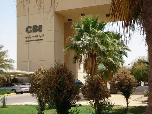 مدخل مبنى عصر لافتتين لكل الأعمال وكلية الاقتصاد، ويحيط به نخيل وأعشاب خضراء وشجيرات، بالإضافة إلى وجود سيارات متوقفة في المشمسة.