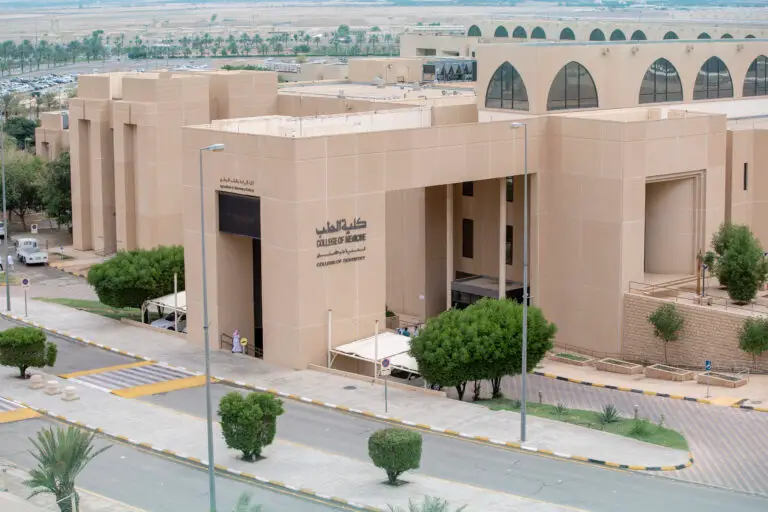 مبنى حديث ذو لون بيج عصر النهضة اسم "كلية الطب" و"كلية طب الأسنان" باللغتين الإنجليزية والعربية، ويحيط به عدد من الأشخاص، وتقع بالقرب منه طريق وممر مشاة بالإضافة إلى مواقف سيارات، وذلك ضمن الحرم الجامعي لجامعة القصيم.