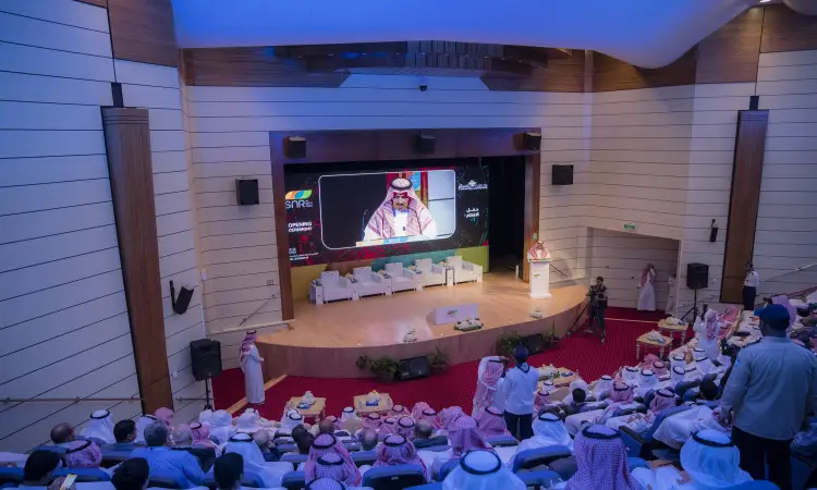 يجتمع جمع غفير من الحضور، مرتدين الزيّ السعودي التقليدي بما في ذلك الشماغ أو الغترة السعودية، جلسات مؤتمر يُعقد في قاعة محاضرات في القصيم. ويتابع الحضور كلمة يلقيها أحد المقصودين من المنصة، بينما تعرض على الشاشة الرئيسية تقرير حول الهدف السابع، ومع ذلك يأتي رجل يرتدي الزي السعودي الرسمي.