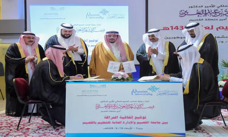 اجتمع عدد من رجال مرتدين الزي السعودي الرسمي، بما في ذلك الشماغ أو الغترة السعودية، في القصيم. وقد جلس على طاولة لتوقيع وثائق، فيما يمنع أن يراقبون سير الأحداث. انتبه إلى الخلفية وشاشة تحمل نصوصاً عربية تبرز الهدف العاشر.
