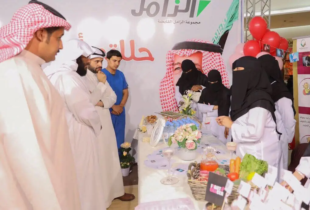 مجموعة من الرجال والسيدات، نشأوا الزي السعودي التقليدي كالشماغ أو الغترة السعودية، بعد أن أصبحوا آمنين الطبيين، الاتصالون حول طاولة تواصل معروضات وثيقة الصلة إلى جانب الزهور بشكل آمن، وذلك من خلال فعالية أُقيمت في مكان مغلق للدفاع عن الهدف الثالث كما ورد في تقرير التوعية الصحية وعن جامعة القصيم.