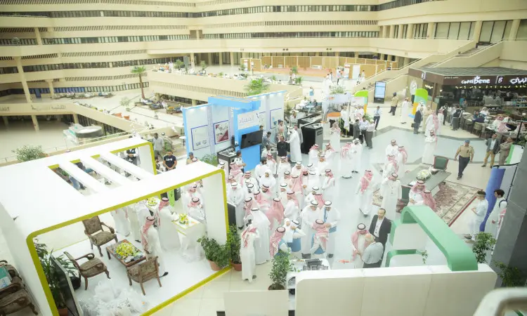 A large number of men, wearing the Saudi Shemagh and Saudi Ghitarah, gathered in an indoor exhibition with various pavilions and displays and a spacious lobby. This is part of the efforts to achieve Goal 12, as outlined in Qassim University's final report.