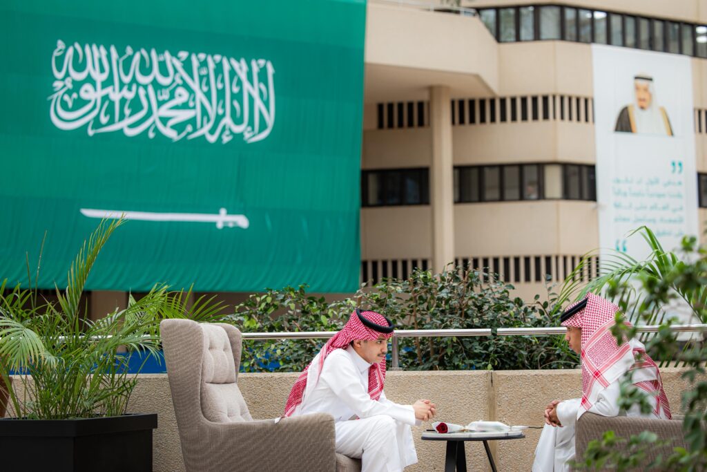 نقاش أكاديمي في جامعة القصيم بمناسبة بداية العام الجامعي الجديد وخلفية تحمل هُوية الجامعة.