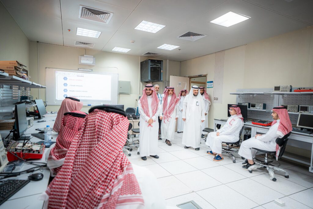 طلبة يتبادلون الحوار والعمل في قاعة دراسية بجامعة القصيم مع عرض حول العام الجامعي الجديد.