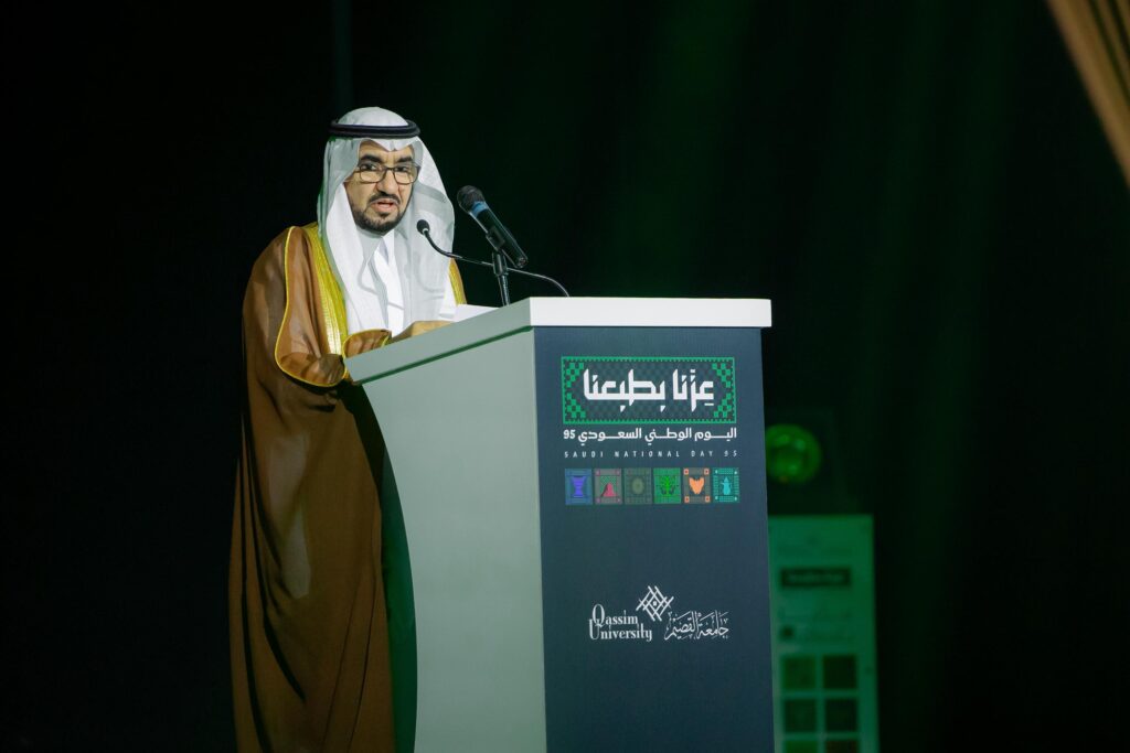 إلقاء كلمة رسمية في فعالية اليوم الوطني بجامعة القصيم تحت إضاءة مميزة.