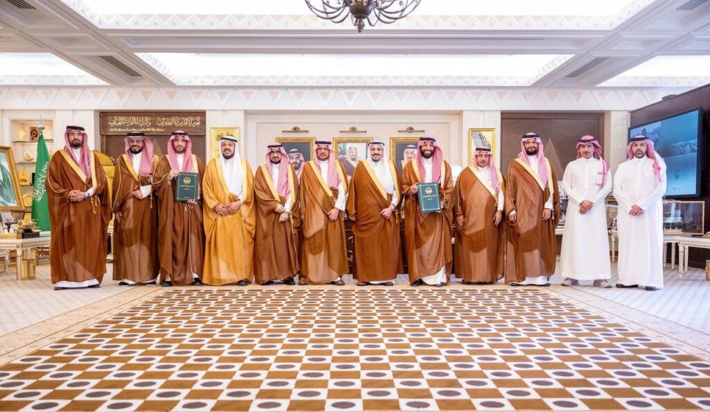 اجتماع رسمي في قاعة جامعة القصيم بحضور شخصيات سعودية لمناقشة مسودة أكاديمية.
