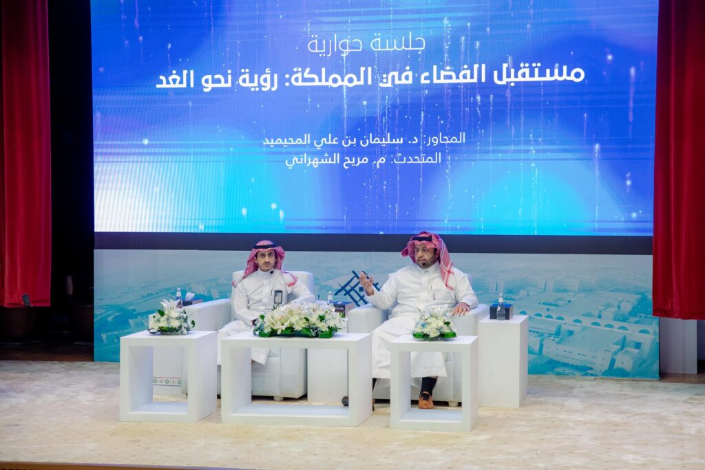 Two participants in a scientific discussion at the Qassim University theater as part of World Space Week.