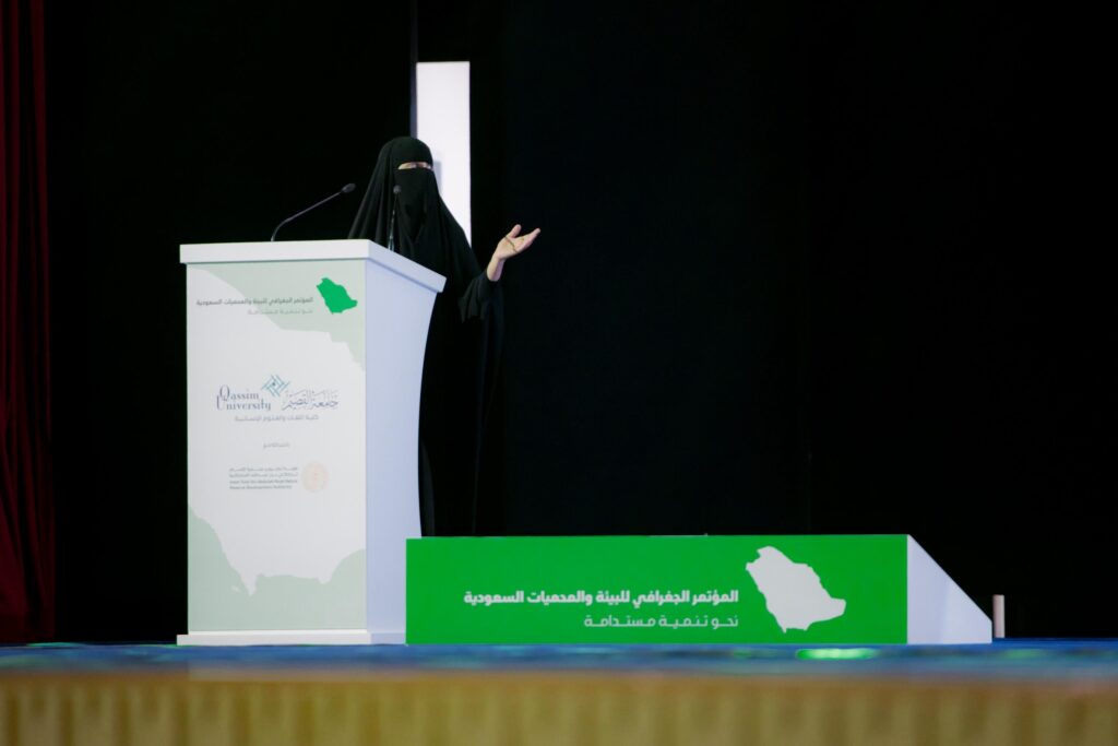 إحدى المشاركات تلقي كلمة خلال المؤتمر الجغرافي بجامعة القصيم عن البيئة والمحميات.