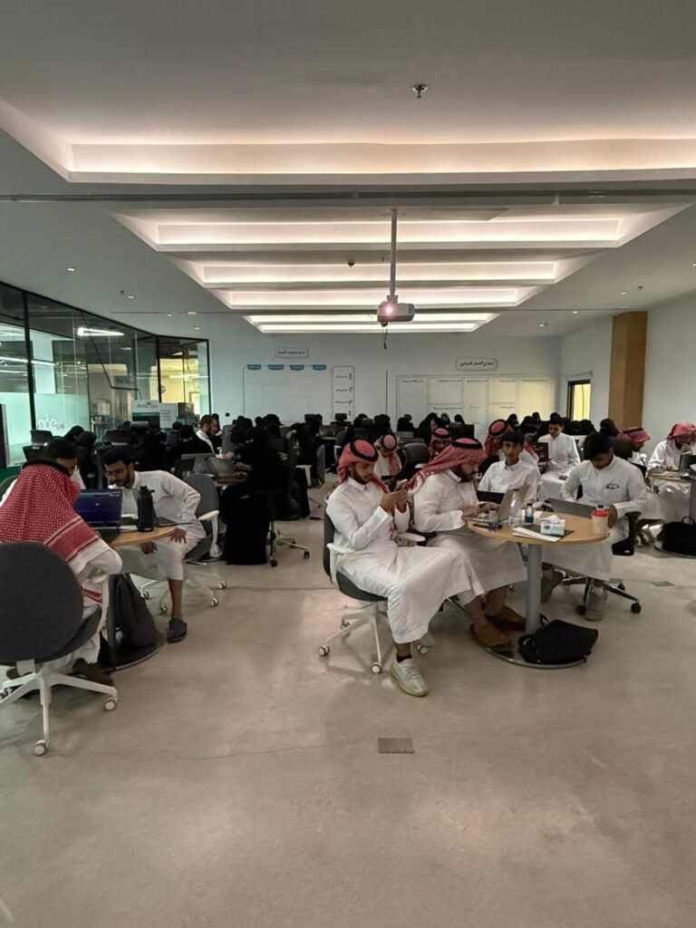 طلاب في قاعة دراسية بجامعة القصيم يناقشون الأمن السيبراني في أكاديمية أكاديمية حديثة.