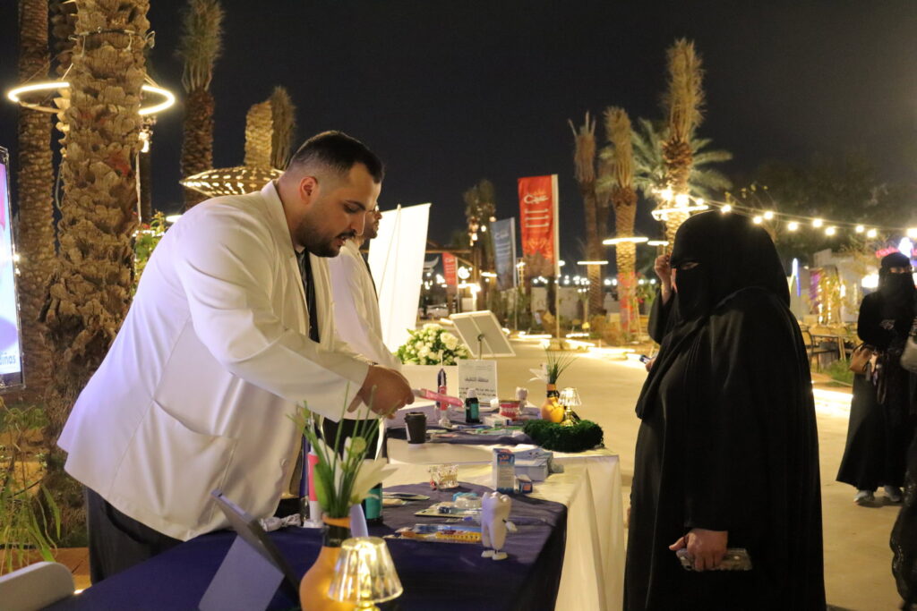 Health awareness at Qassim University in the evening between palm trees and lighting, with a community presence.