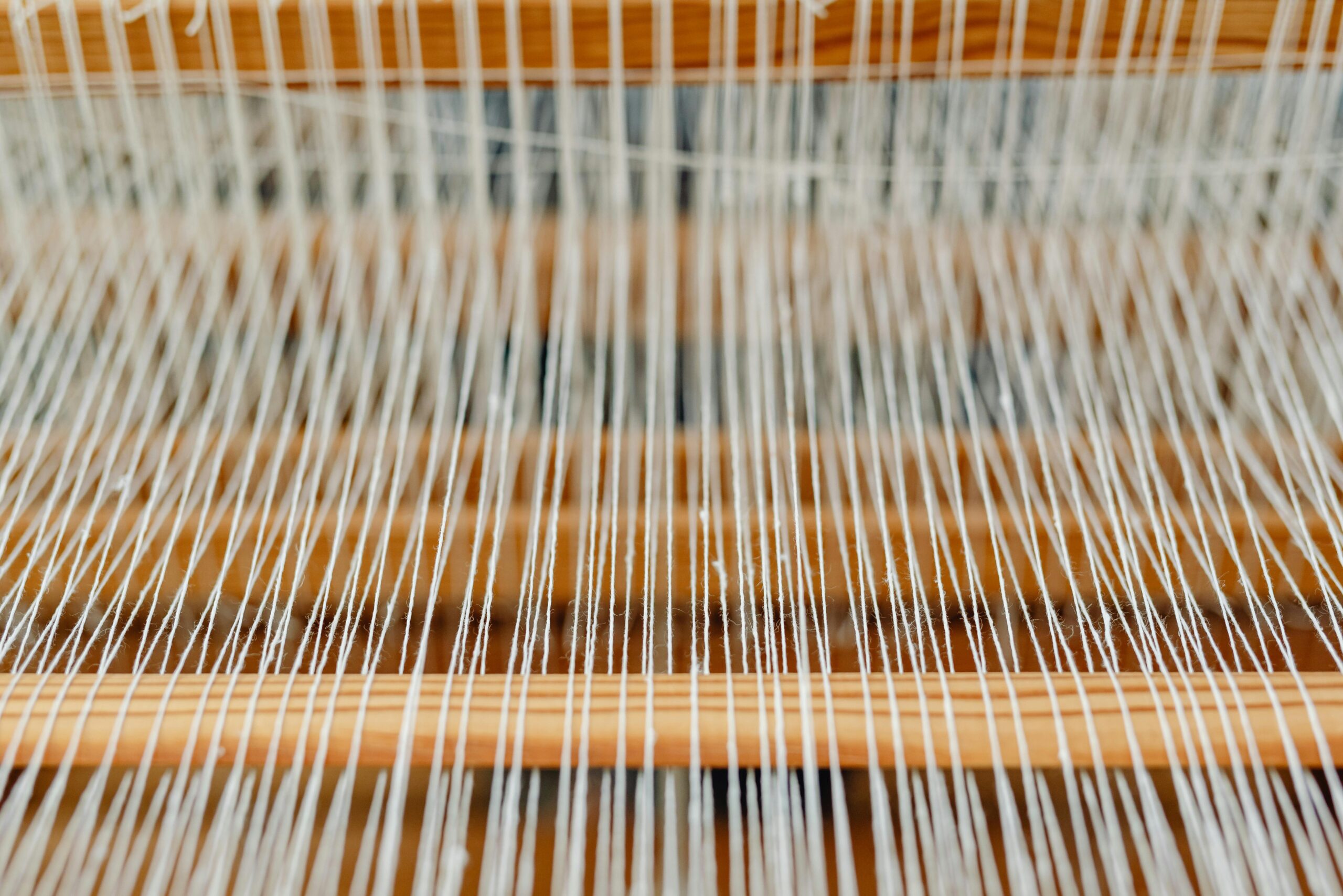 A detailed demonstration of white textile threads on a nolby at the Crafts Lab at Al-Qassim University.