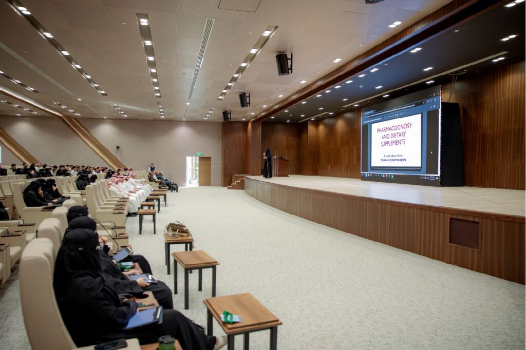 محاضرة علمية حول الصيدلة والمكملات الغذائية لطلاب جامعة القصيم في قاعة حديثة.