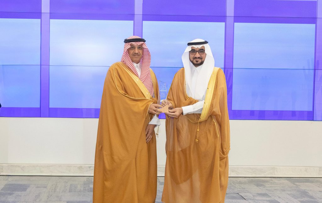 شركاء العمل التطوعي بجامعة القصيم أمام لوحة الشراكة مع وزير التعليم السعودي.