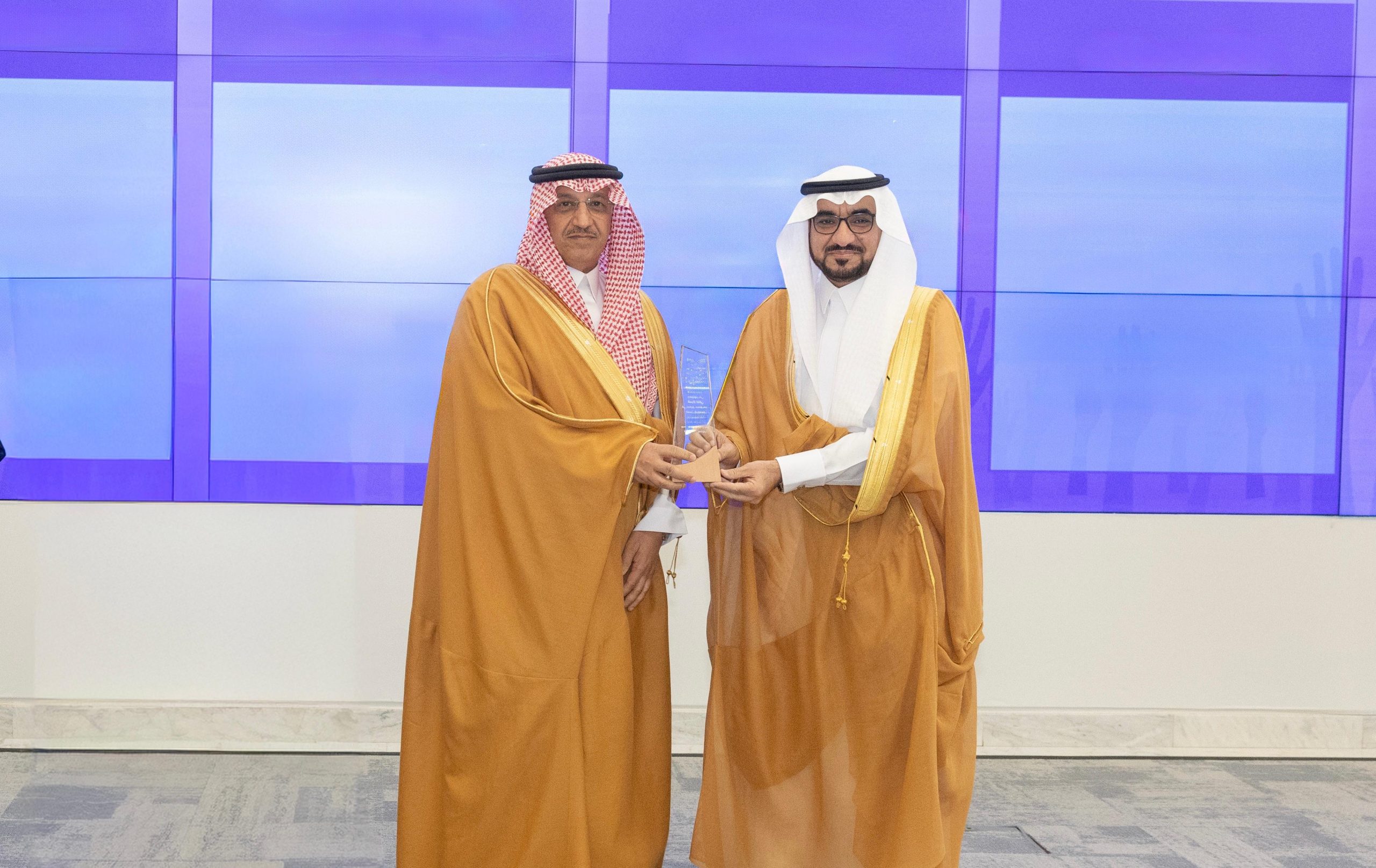 شركاء العمل التطوعي بجامعة القصيم أمام لوحة الشراكة مع وزير التعليم السعودي.