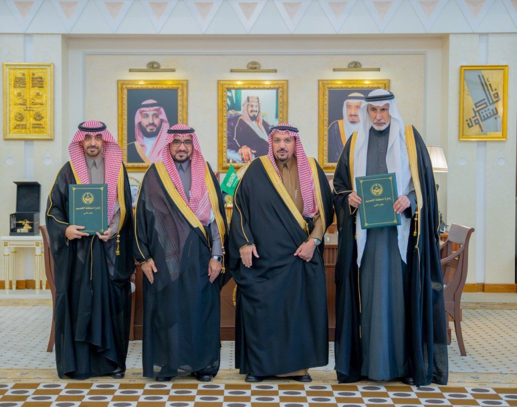 اتفاقية رسمية بين ممثلي جامعة القصيم في قاعة تحمل صور القيادة السعودية.