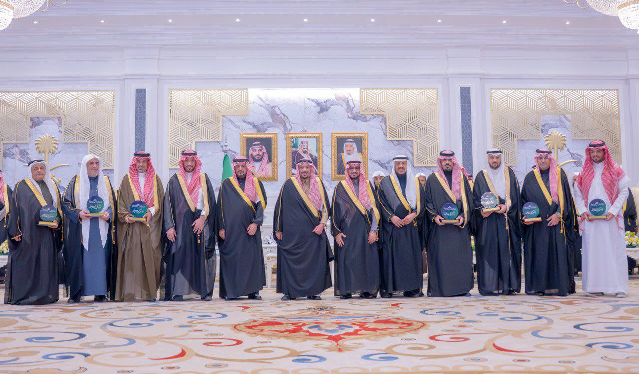 A formal academic honor at Qassim University in the presence of the region's emir and flags for the university and the applied college.