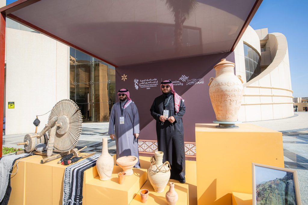 عرض للحرف اليدوية السعودية في فعالية القصيم بخلفية معمارية حديثة.