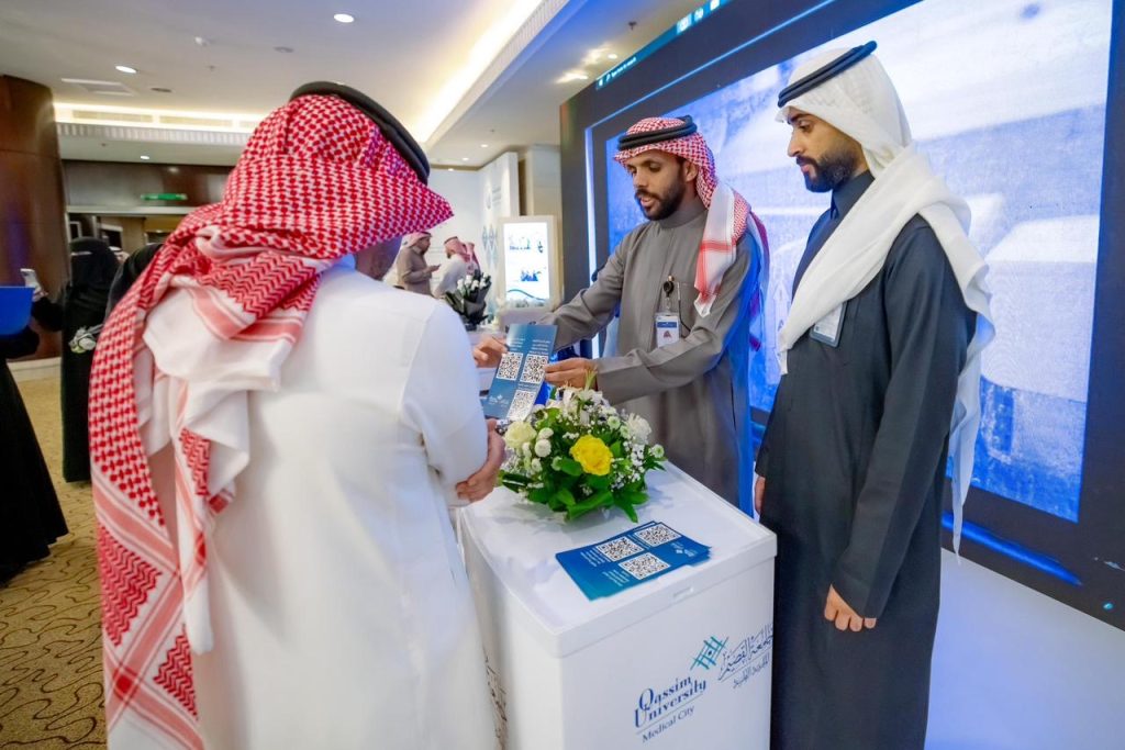 A discussion on health projects at the Qassim University forum, with informational brochures distributed to visitors.