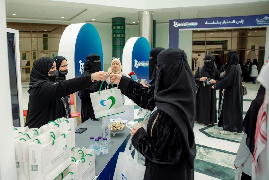 Distributing welcome bags at the registration desk as part of an academic event at Qassim University.