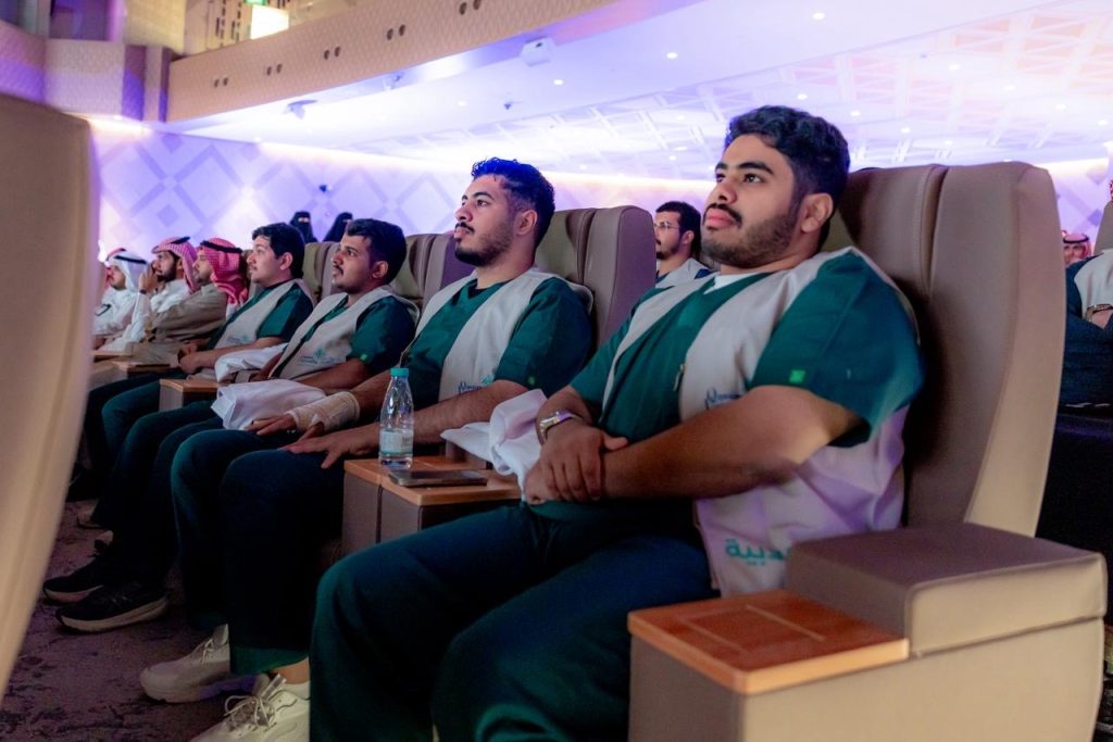 حفل تخريج جامعة القصيم بحضور طلاب يتابعون الفعالية في قاعة حديثة.