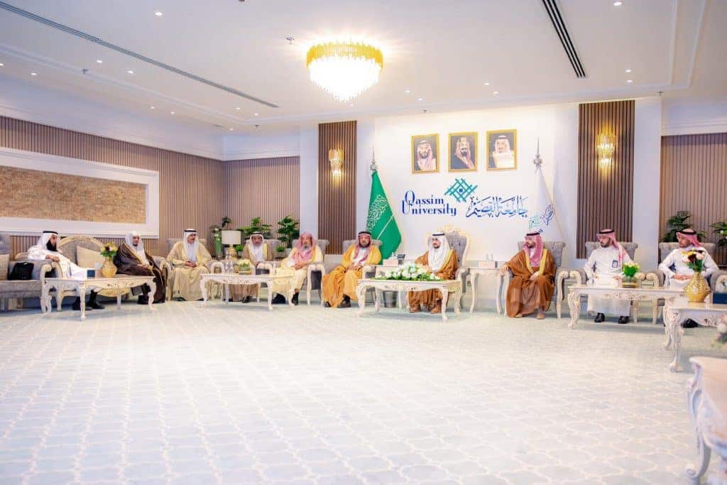 حفل رسمي في جامعة القصيم بقاعة أنيقة مزينة بالأعلام والشعارات يعكس هوية الجامعة.