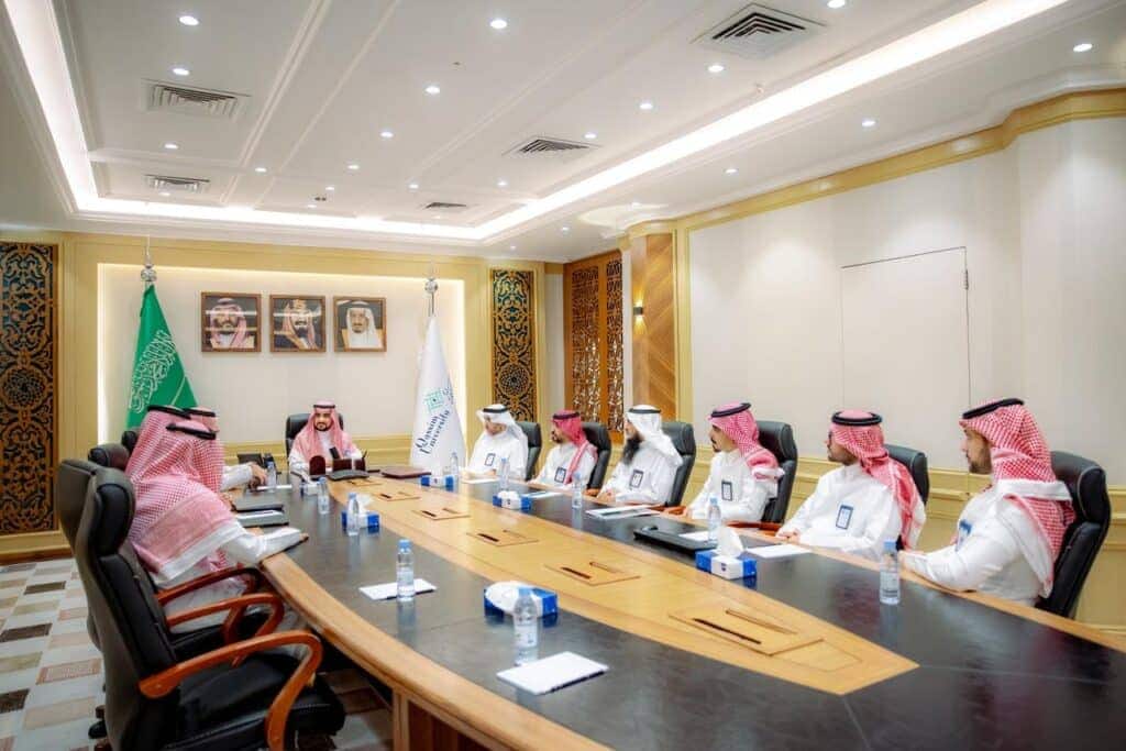 اجتماع استثماري رسمي بجامعة القصيم في قاعة تحمل رموز وهوية المجتمع السعودي.